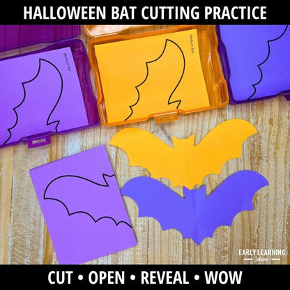 Purple, yellow, and blue bat cutouts with fold lines displayed next to template pages on wood surface for cutting practice