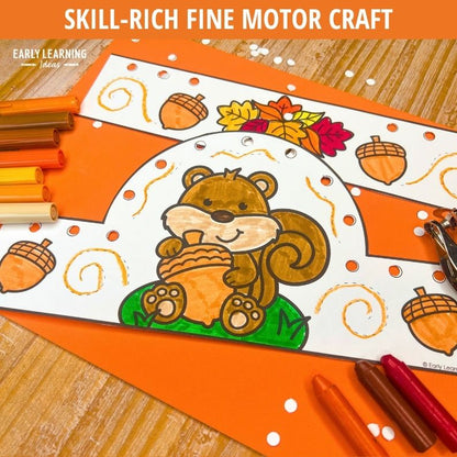 Colorful fall-themed crown craft with smiling squirrel design, orange markers, and acorn decorations for fine motor practice