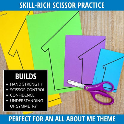 Colorful folded paper houses in yellow, green, purple, and blue with scissors cutting along outlined edges on wood surface.
