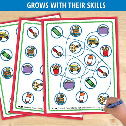 Child's hand drawing blue lines connecting school supply icons on laminated worksheet with red and green borders